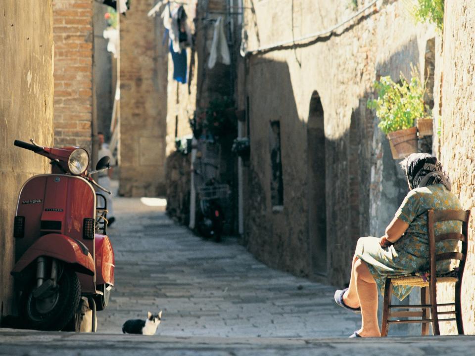 Old woman and cat next to scooter in Italian street