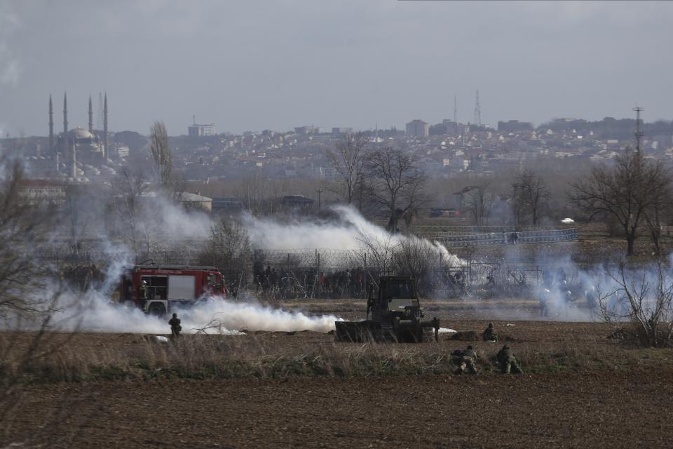 Greek army take positions as migrants gather at a border fence on the Turkish side, during clashes at the Greek-Turkish border in Kastanies, Evros region, on Saturday, March 7, 2020. Thousands of refugees and other migrants have been trying to get into EU member Greece in the past week after Turkey declared that its previously guarded borders with Europe were open. (AP Photo/Giannis Papanikos)