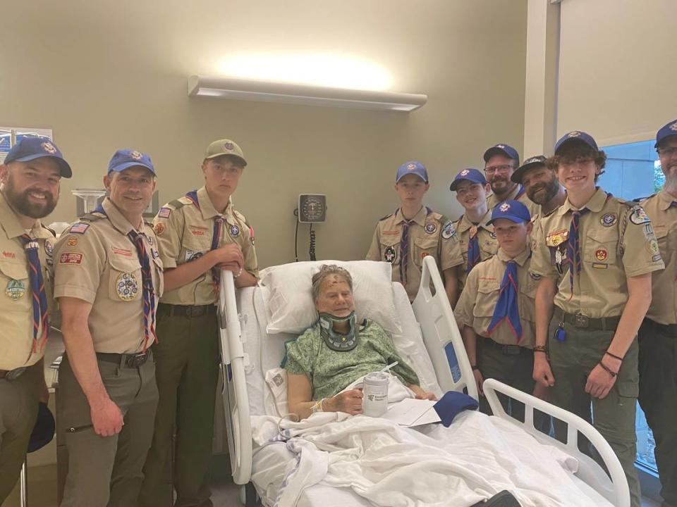 Eric Valentine poses with members of Troop 77 from his hospital bed Monday evening. Nearly two dozen members of the troop were out on a canoe trip on May 6 when they were flagged down and able to help Valentine after he fell off a hill.