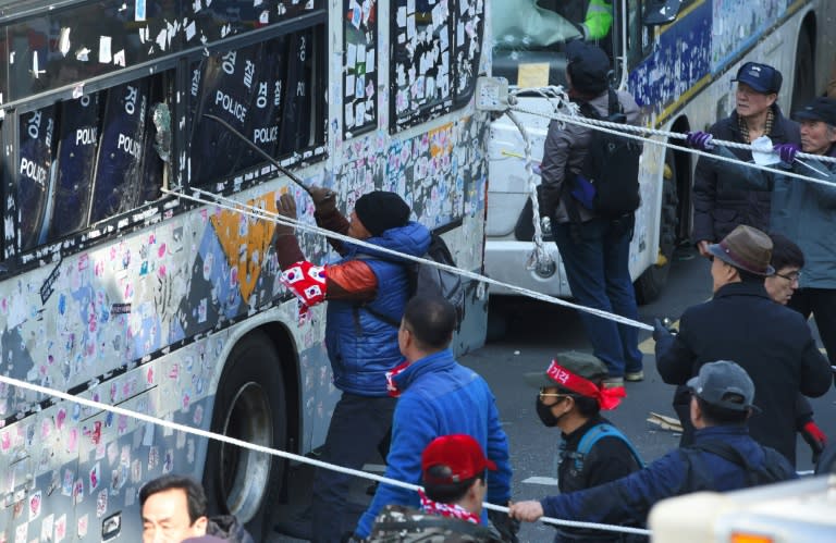 Supporters of South Korean President Park Geun-Hye attack a police bus in Seoul on March 10, 2017 after the announcement of the Constitutional Court over her impeachment
