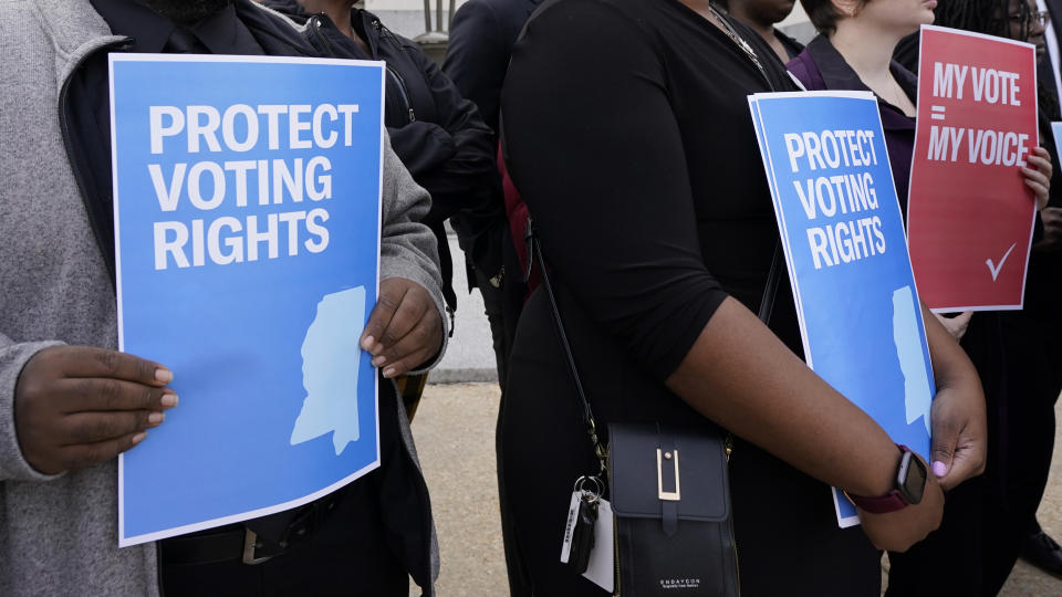 FILE - Members of voting rights group hold signs calling for protection of voting rights while joining others at a news conference in Jackson, Miss., Dec. 7, 2023. Republicans are challenging extended mail ballot deadlines in at least two states in a move that could have severe implications for mail voting nationwide ahead of this year's presidential election. A lawsuit filed last week in Mississippi follows a similar one last year in North Dakota, both brought in heavily Republican states before conservative federal courts. (AP Photo/Rogelio V. Solis, File)