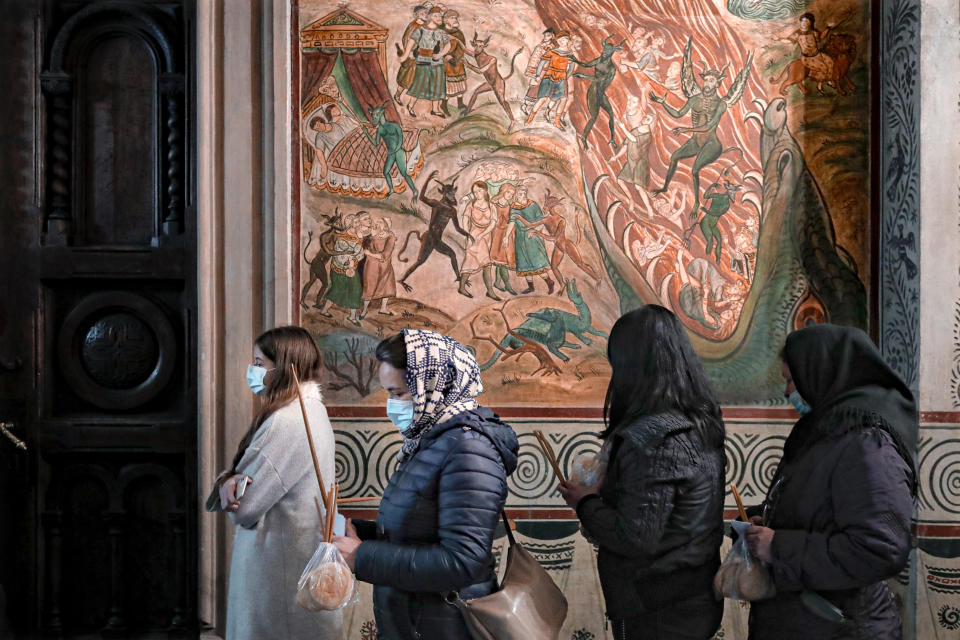 Orthodox worshipers, wearing masks for protection against the COVID-19 virus, wait for a religious service in the Black Sea port of Constanta, Romania, late Tuesday, May 26, 2020. (AP Photo/Vadim Ghirda)