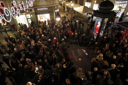 People gather around lit candles arranged to form the phrase "I am Charlie" as a tribute to victims of a shooting by gunmen at the offices of French satirical weekly Charlie Hebdo, in front of the French cultural centre in Belgrade January 8, 2015. REUTERS/Djordje Kojadinovic