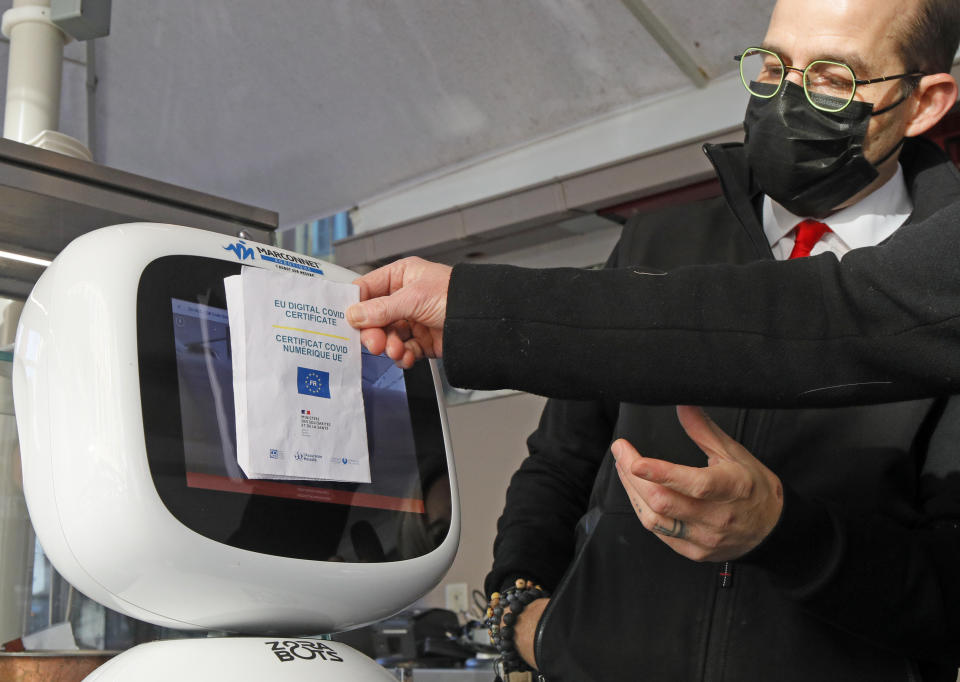 A machine checks a man's vaccine pass, at a restaurant in Lille, northern France, Monday, Jan. 24, 2022. Unvaccinated people are no longer allowed in France's restaurants, bars, tourist sites and sports venues, as a new law came into effect Monday requiring a "vaccine pass" that is central to the government's anti-virus strategy. (AP Photo/Michel Spingler)