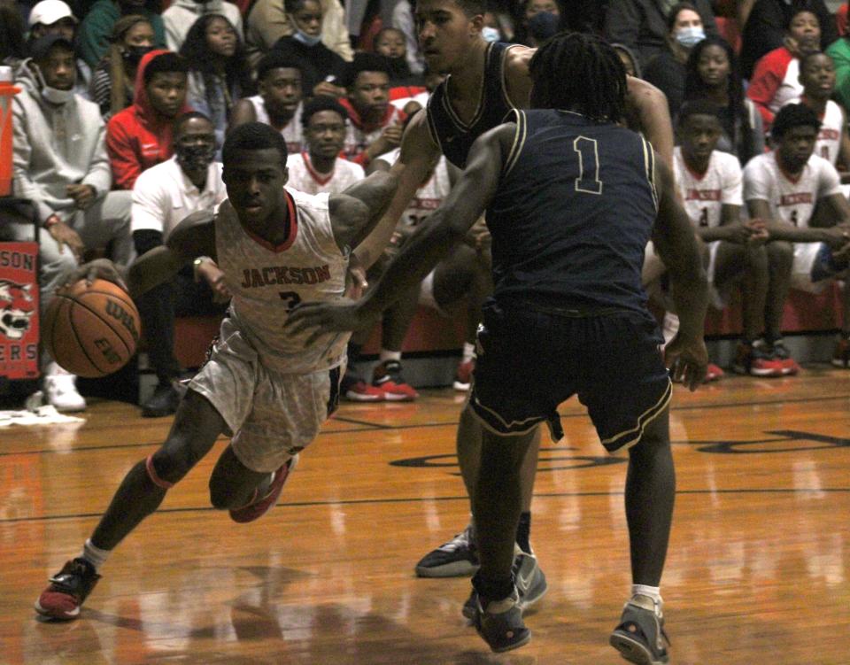 Jackson point guard Kevin Odom (3) dribbles as Paxon guard Abraham Garjah (1) and forward Saryn Hatcher (21) defend during the Gateway Conference high school boys basketball final.