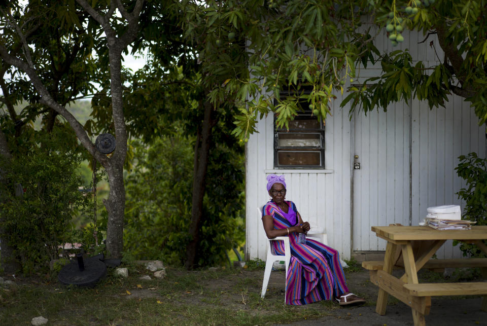 Yolanda Constant, a member of the Ras Freeman Foundation for the Unification of Rastafari, sits under a mango tree as she waits for service to start in the tabernacle on Sunday, May 14, 2023, in Liberta, Antigua. (AP Photo/Jessie Wardarski)