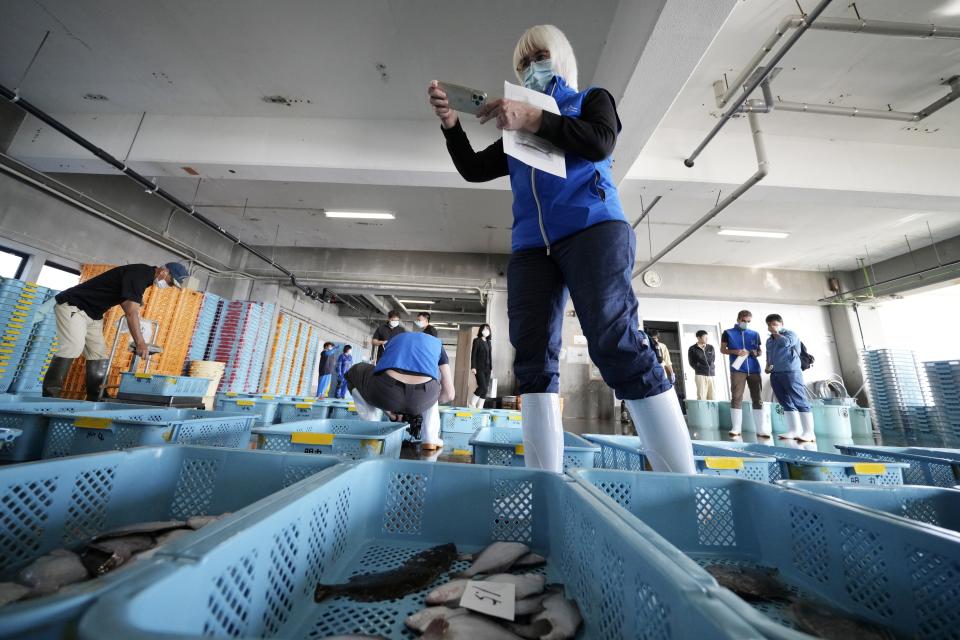 Iolanda Osvath, research scientist, a member of experts from the International Atomic Energy Agency (IAEA) observes the inshore fish during a morning auction at Hisanohama Port in Iwaki, northeastern Japan Thursday, Oct. 19, 2023. They are visiting Fukushima for its first marine sampling mission since the Fukushima Daiichi nuclear power plant started releasing the treated radioactive wastewater into the sea. (AP Photo/Eugene Hoshiko, Pool)