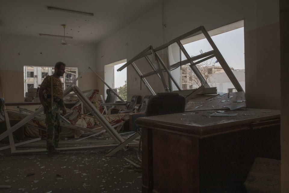 A solider looks at damage after a deadly attack on the Sheikh Othman police station, in Aden, Yemen, Thursday, Aug. 1, 2019. Yemen's rebels have fired a ballistic missile at a military parade in the southern port city of Aden as coordinated suicide bombings targeted the police station in another part of the city. The attacks killed over 50 people and wounded dozens. (AP Photo/Nariman El-Mofty)