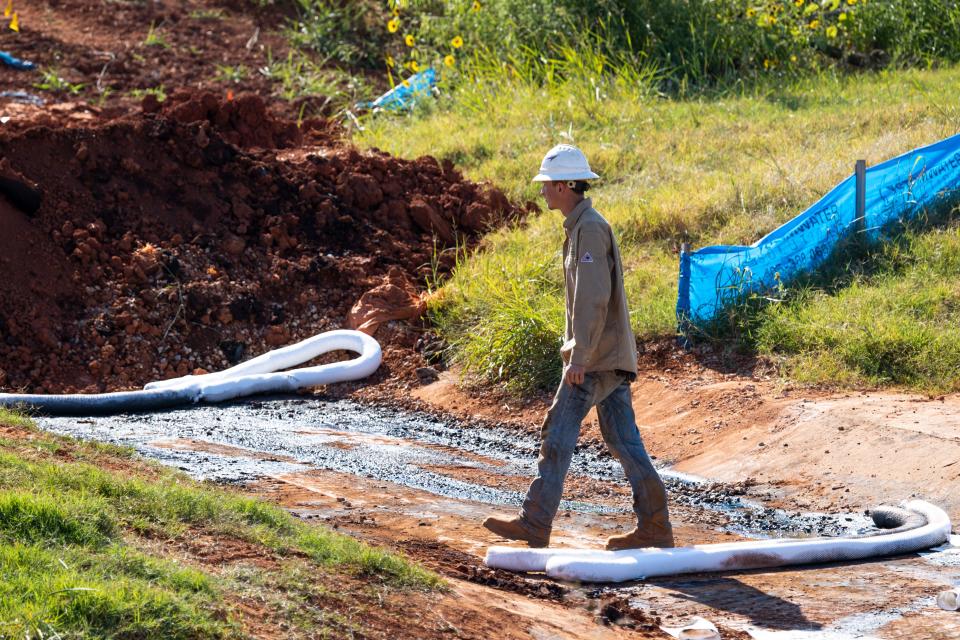 A worker checks the progress of cleaning up contamination near the site of a northwest Oklahoma City oil spill. Cleanup efforts are expected to last at least another several days.