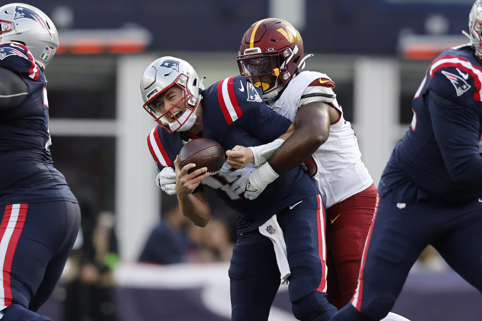 Washington Commanders defensive end KJ Henry, center right, hits New England Patriots quarterback Mac Jones, center left, resulting in a roughing the passer call in the second half of an NFL football game, Sunday, Nov. 5, 2023, in Foxborough, Mass. (AP Photo/Michael Dwyer)