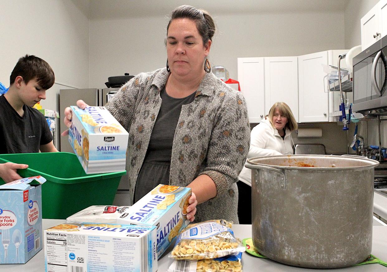 Volunteer Kortni Peek places food on the serving counter at the Bedford Men's Warming Shelter Monday evening. The shelter will receive a generous donation from the Dunn Foundation. The check presentation will occur at the shelter Friday at noon. There will be a lunch afterwards, and the event is open to the public. Peek's son Levi Peek is in the background at left in the picture, and the shelter's Executive Director Heather Flynn can be seen in the background at right.