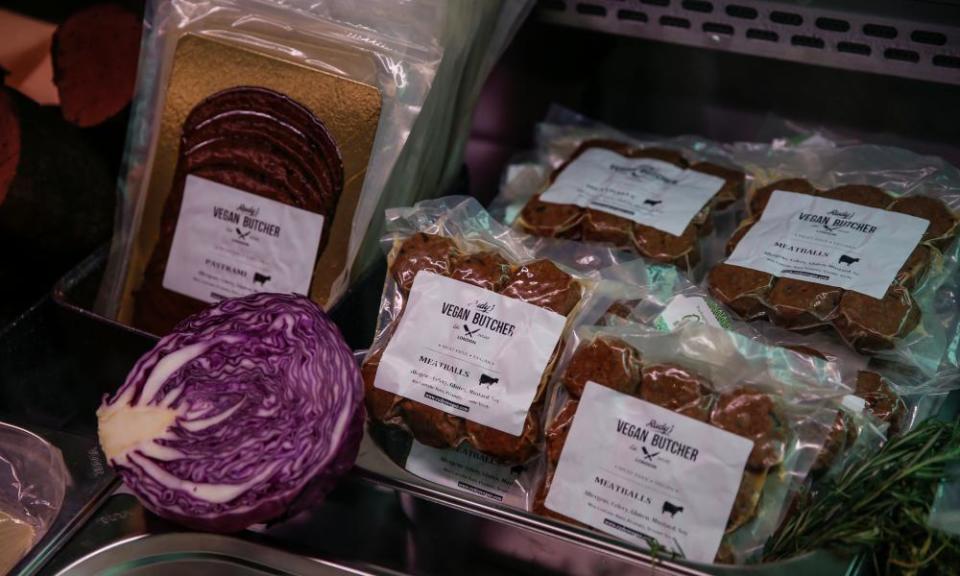 Close-up of a shelf of plastic-wrapped products including 'meatballs', with half a red cabbage placed as decoration