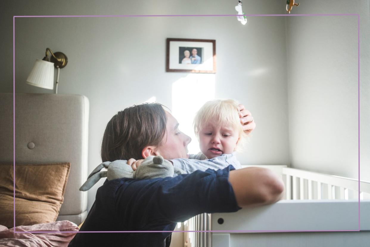  Man comforting toddler in cot. 