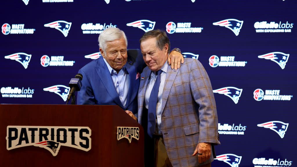 patriots owner robert kraft hugging bill belichick behind a microphone podium