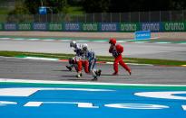 Track staff members pick up a piece of a car on the race tracks following a collision at the start of the Formula One Styrian Grand Prix race on July 12, 2020 in Spielberg, Austria. (Photo by LEONHARD FOEGER / POOL / AFP) (Photo by LEONHARD FOEGER/POOL/AFP via Getty Images)