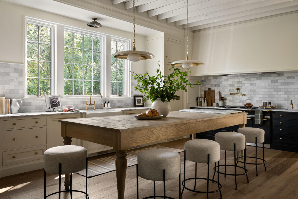  A neutral kitchen with a large kitchen island with a vase of foliage in the middle. 