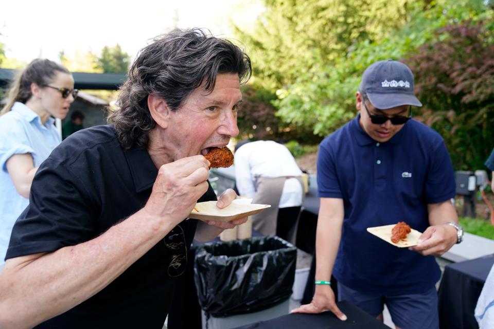 Herb Karlitz, founder of the Celebrity Chefs and Friends golf and tennis tournament, tries the chili fried chicken from Pecking House during the tournament on Monday, May 8, 2023, in Demarest.