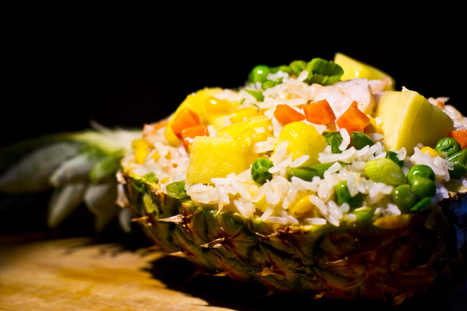<p>This one is a favourite among many Thai food lovers. What makes the dish unique, is it’s final presentation. Pineapple Rice is usually served in the fruit itself – the shell of the pineapple makes for the serving bowl. In a small bowl, whisk together soy sauce, sesame oil, ginger powder and white pepper and keep aside. Heat oil in a large wok over medium high heat. Add some chopped garlic, onion and cook till onions brown out. Add chicken/ shrimp pieces. Then add chopped carrots, corns, peas and cook, stirring constantly until vegetables are tender. Ensure that if shrimps are added, they do not overcook. Add pre cooked rice, pineapple, green onions and the mixture previously set aside in the bowl. Cook for 2 minutes and serve immediately in a Pineapple shell. “Creative Commons Pineapple Fried Rice” by Ruocaled is licensed under CC BY 2.0 </p>