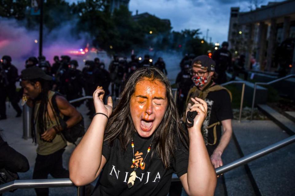 A woman reacts after being sprayed by pepper spray next to the Colorado State Capitol in Denver.