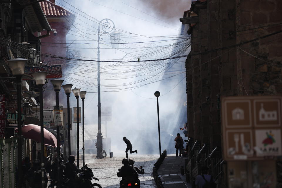 A supporter of former President Evo Morales is silhouetted against a wall of tear gas as he runs from advancing security forces during clashes in La Paz, Bolivia, Friday, Nov. 15, 2019. Morales stepped down on Sunday following nationwide protests over suspected vote-rigging in an Oct. 20 election in which he claimed to have won a fourth term in office. An Organization of American States audit of the vote found widespread irregularities. (AP Photo/Natacha Pisarenko)