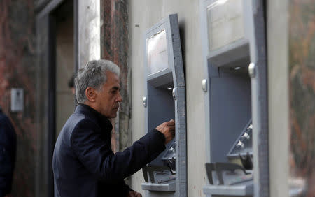 A Palestinian man checks his balance via an automated teller machine (ATM) outside a bank in Gaza City April 12, 2018. REUTERS/Ibraheem Abu Mustafa