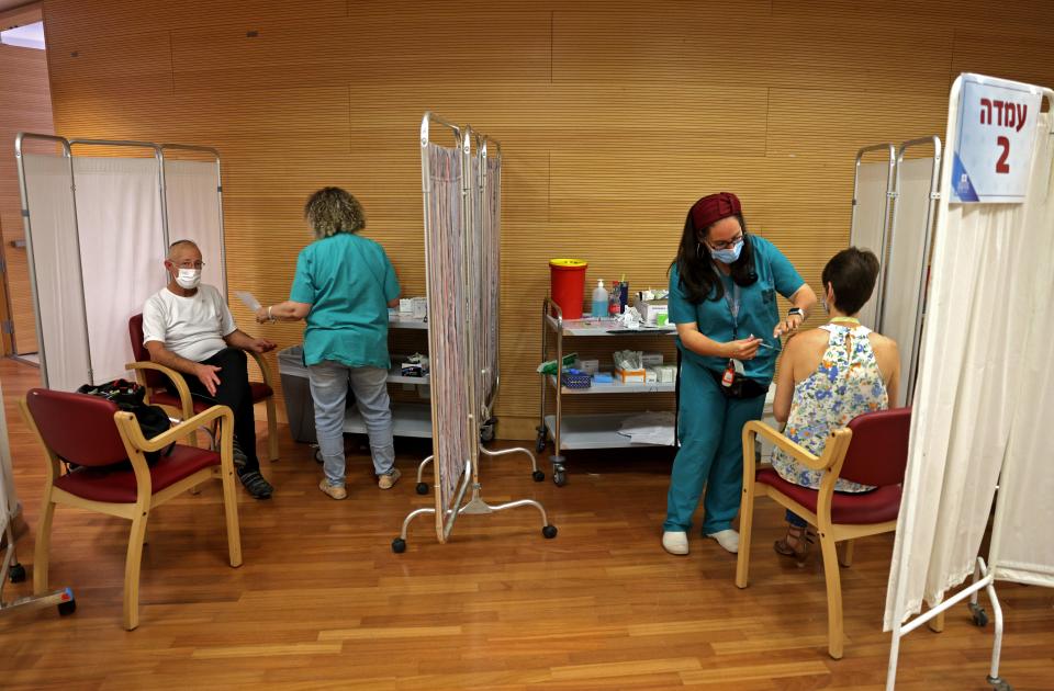 Israeli medics administer a booster jab of the COVID vaccine to members of medical teams at the a hospital in Jerusalem on August 15, 2021. (Photo by Menahem KAHANA / AFP)