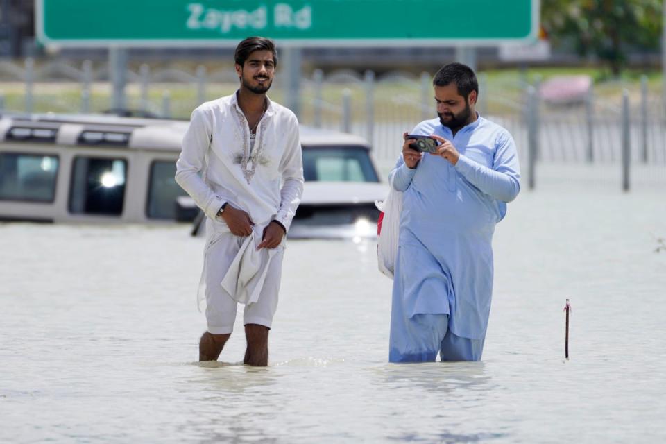 Two men walk through floodwater in Dubai, United Arab Emirates, Wednesday, April 17, 2024 (AP)