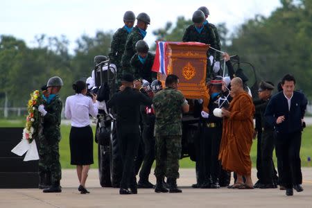 A buddhist monk leads an honour guard carrying the coffin of Samarn Poonan, 38, a former member of Thailand's elite navy SEAL unit who died working to save 12 boys and their soccer coach trapped inside a flooded cave, at Chiang Rai airport, Thailand, July 6, 2018. REUTERS/Stinger