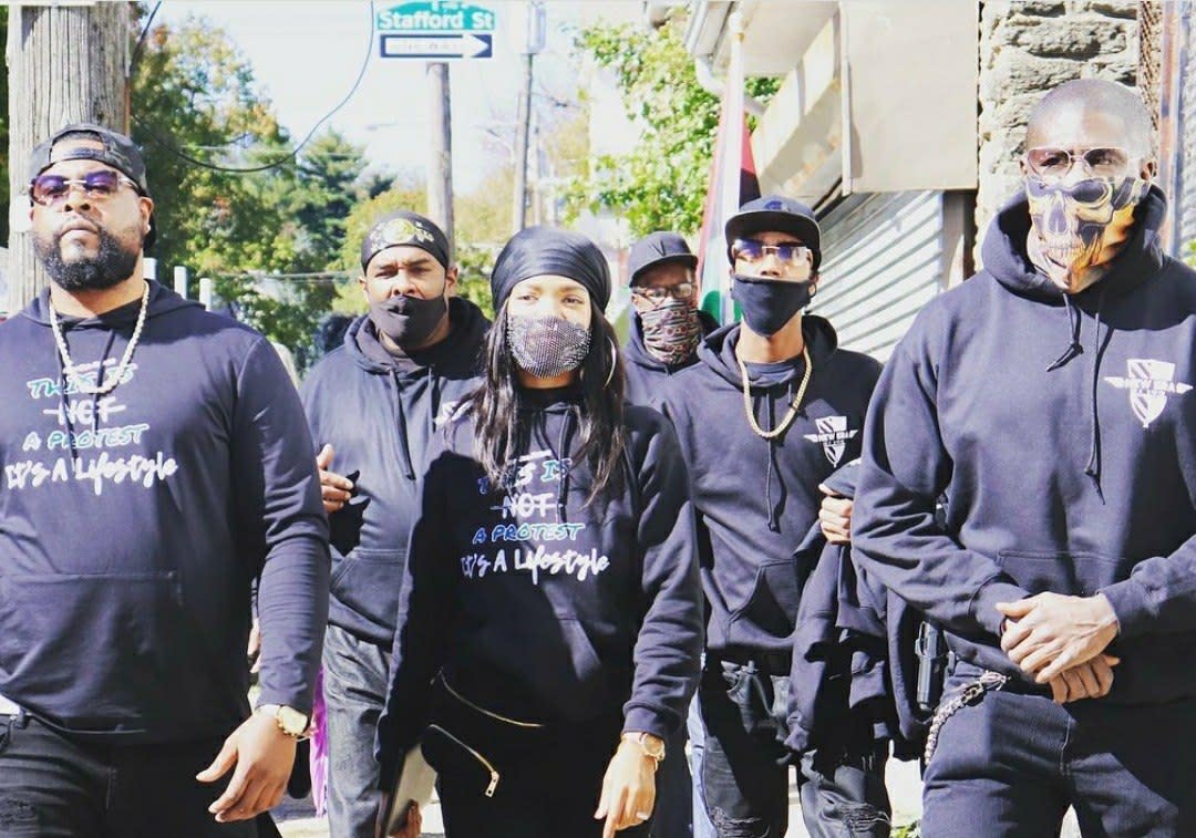 Six members of New Era Detroit, some in masks, walk the streets of Detroit, Mich. with founder Zeek Williams.