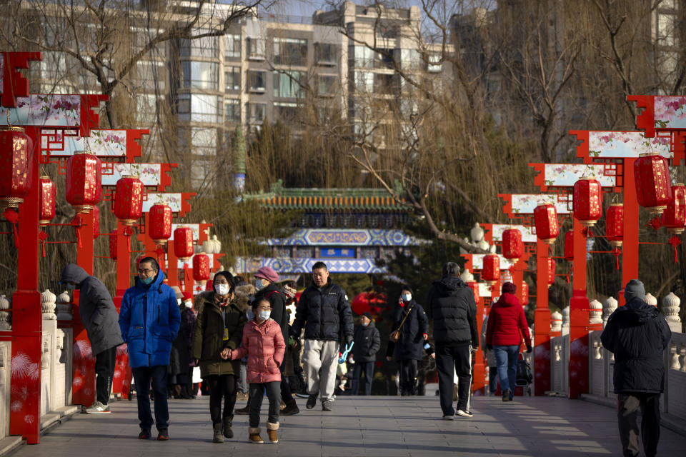Visitors walk across a bridge decorated with lanterns at a public park in Beijing on the first day of the Lunar New Year holiday, Sunday, Jan. 22, 2023. (AP Photo/Mark Schiefelbein)