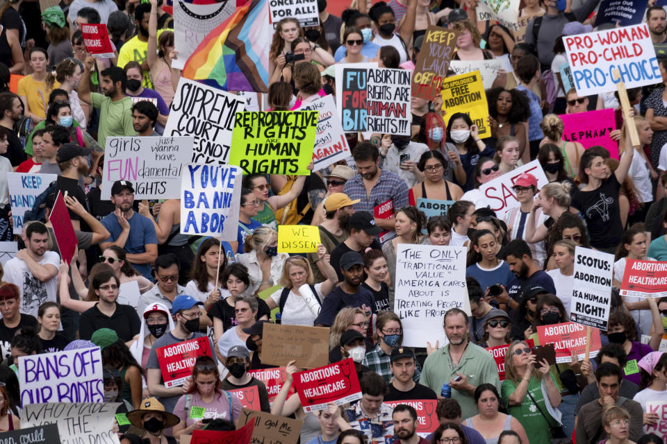 A large crowd holding up signs such as "Bans off our bodies" and "Reproductive rights are human rights"