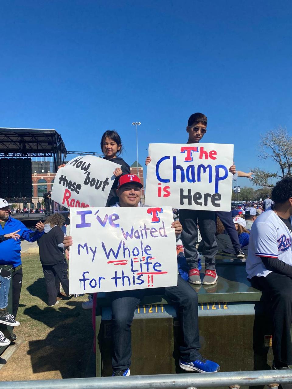 Thomas Vasquez and his children pose with homemade Rangers signs before the World Series victory parade.