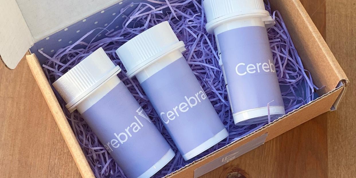 A box of three bottles of Cerebral-labeled medications sits on a wooden surface.