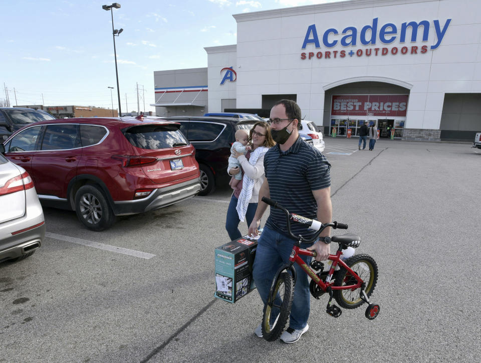 FILE - In this Friday, Nov. 27, 2020, file photo, Aaron and Jessica Elder, of Hartford, carrying Boyd, 7 months, purchased two bikes for their children for Christmas presents while shopping on Black Friday at Academy Sports + Outdoors in Owensboro, Ky. A Federal Reserve survey of business conditions around the country found that economic activity in several regions was slowing in November as coronavirus cases surged. The report, released Wednesday, Dec. 2, 2020, and known as the beige book, will be used by Fed officials when they hold their last meeting of the year on Dec. 15-16 to discuss possible changes to the central bank's interest-rate policies. (Alan Warren/The Messenger-Inquirer via AP, File)