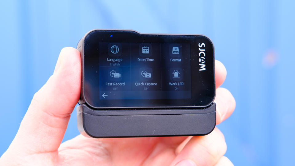 A photo of the SJCAM Sj20 being held up with the rear screen showing against a blue backdrop.