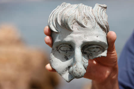 An Israel Antiquities Authority (IAA) employee holds a part of a statue that according to the IAA, was recovered from a merchant ship dated 1600 years in the ancient harbor in the Caesarea National Park May 16, 2016. REUTERS/ Baz Ratner