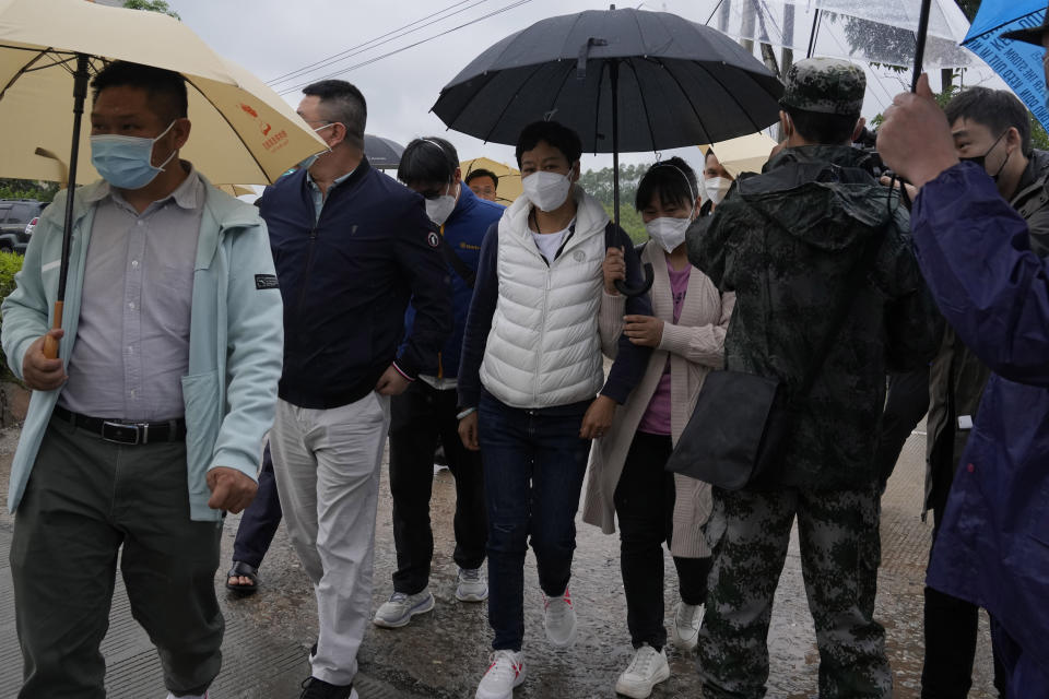 Relatives of passengers onboard the China Eastern Flight 5735 arrive near the crash site, Wednesday, March 23, 2022, Lu village, in southwestern China's Guangxi province. The search for clues into why a plane made an inexplicable dive and crashed into a mountain in southern China was suspended Wednesday as rain slicked the debris field and filled the red-dirt gash formed by the plane's fiery impact. (AP Photo/Ng Han Guan)