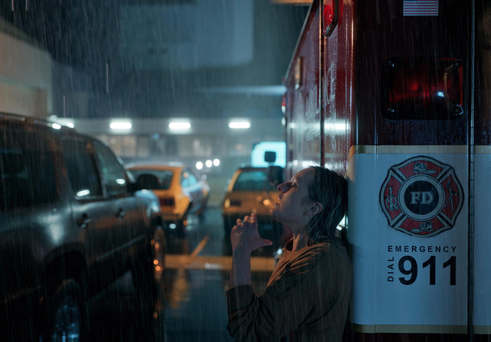 person leaning against a fire truck in the rain