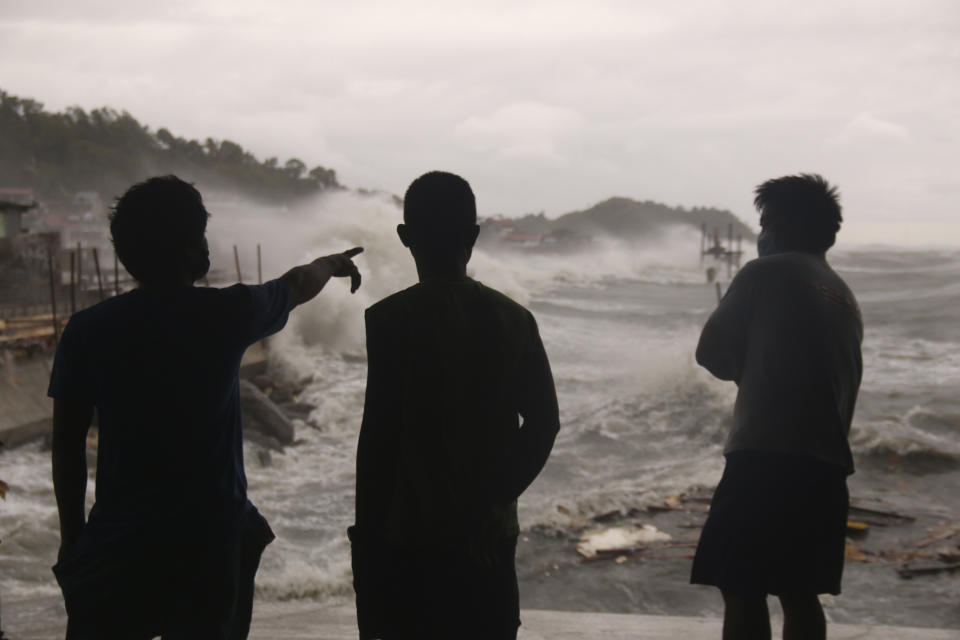 Men watch as strong waves caused by typhoon Vongfong batter the coastline of Catbalogan city, Western Samar province, eastern Philippines, Thursday, May, 14, 2020. A strong typhoon slammed into the eastern Philippines on Thursday after authorities evacuated tens of thousands of people while trying to avoid the virus risks of overcrowding emergency shelters. (AP Photo/Simvale Sayat)