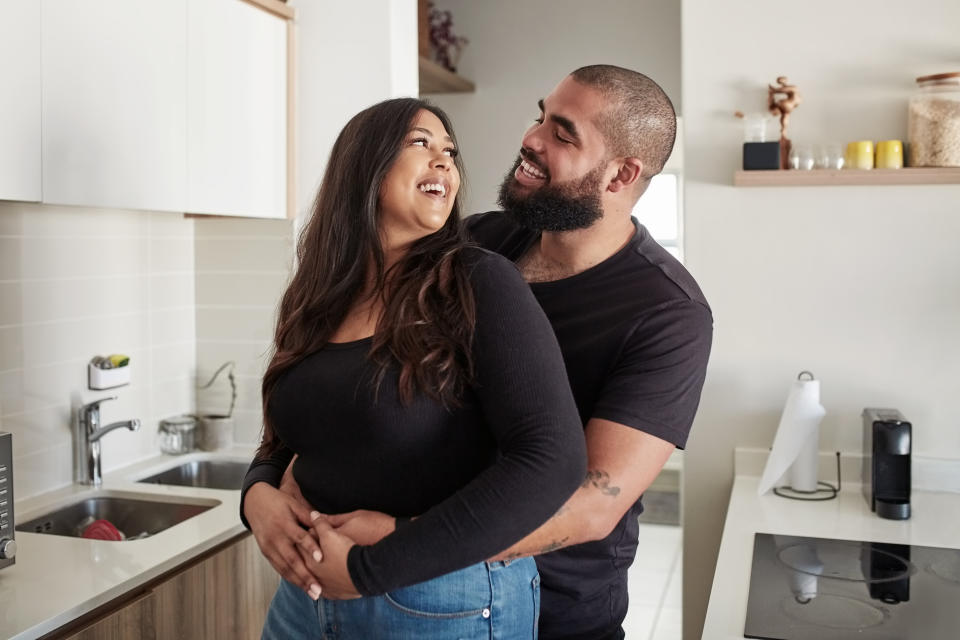A smiling man and woman hugging in the kitchen