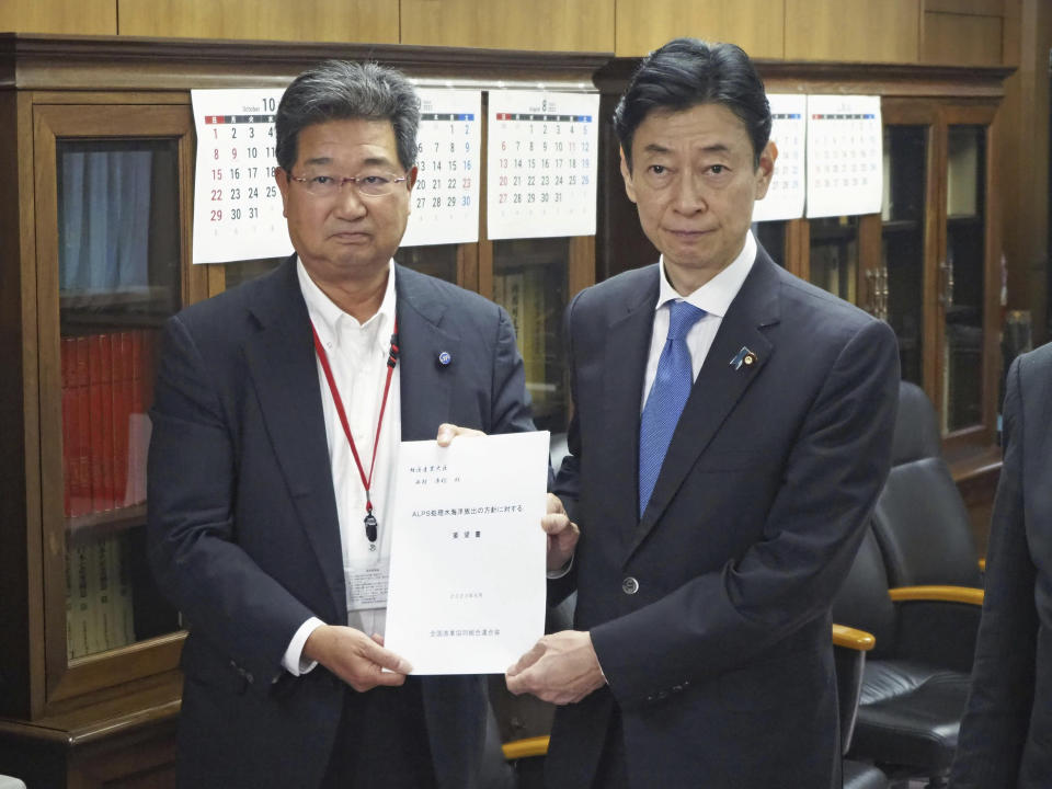 Masanobu Sakamoto, left, head of Japanese national fisheries cooperatives, meets with Japan's Industry Minister Yasutoshi Nishimura, right, at the latter's ministry in Tokyo, Thursday, June 22, 2023. Sakamoto, president of JF Zengyoren, has reiterated his group’s rejection to Japan’s planned discharge of treated radioactive water into sea from the tsunami-wrecked Fukushima nuclear power plant, demanding the government take full responsibility over possible negative impact on the industry.(Kyodo News via AP)