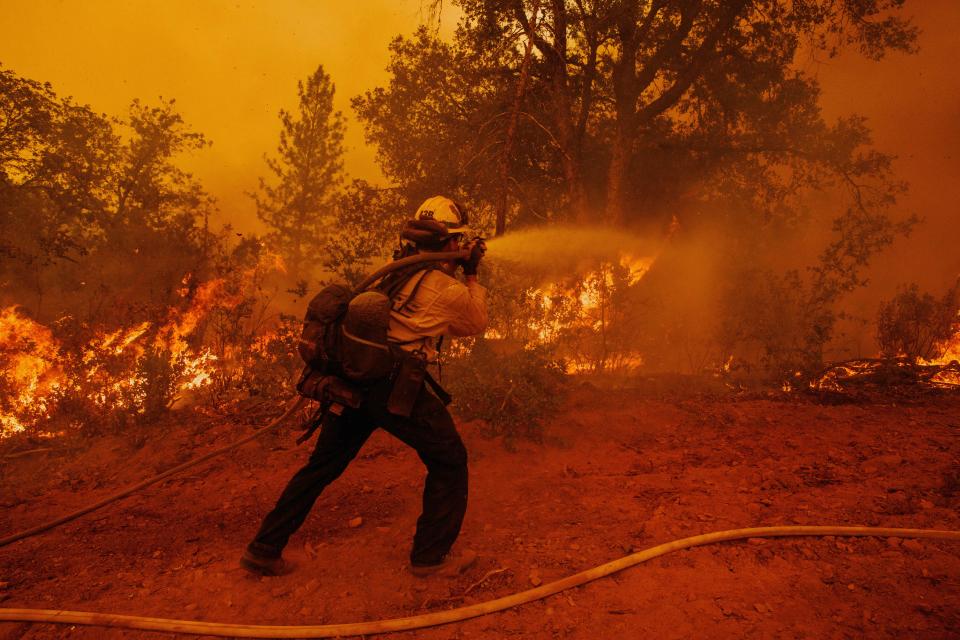 David Stiles douses flames while battling the Oak Fire in unincorporated Mariposa County, Calif.