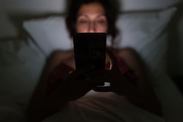 <p>Getty</p> Woman using her smart phone in bed before going to sleep