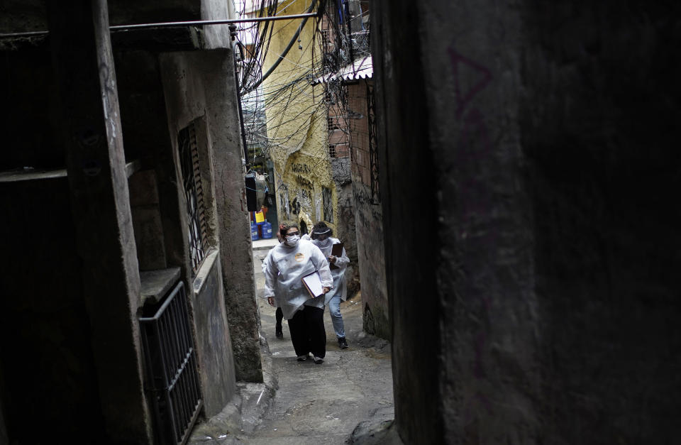 Health workers walk through the Rocinha slum to test people for COVID-19 and set up future appointments as part of a rapid test campaign by the civilian organization "Bora Testar," or "Let's Test" in Rio de Janeiro, Brazil, Thursday, Oct. 8, 2020. Financed by crowdfunding and donations, the organization aims to test up to 300 people in the slum. (AP Photo/Silvia Izquierdo)