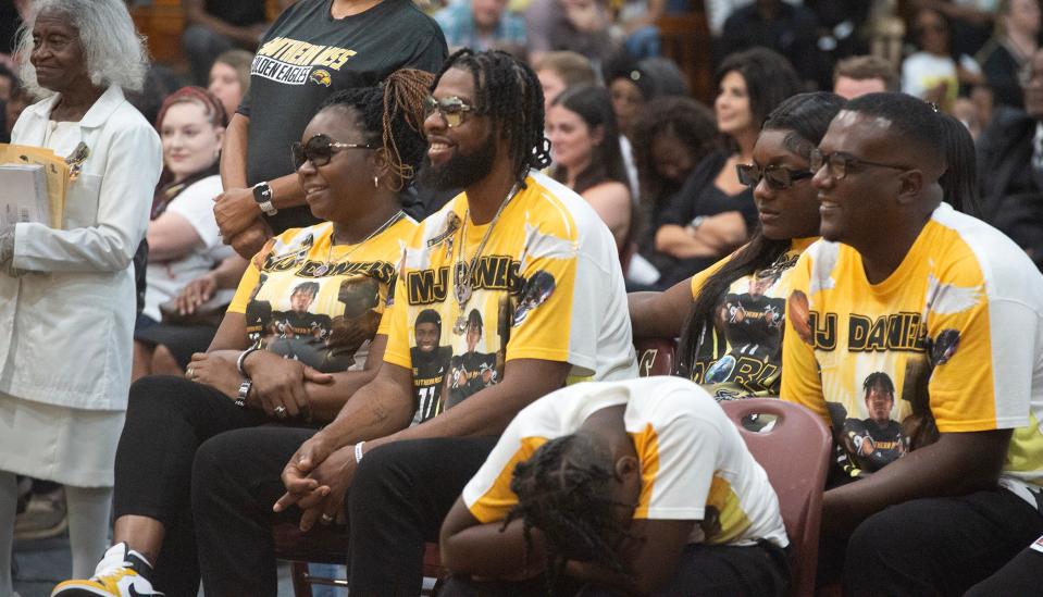 The parents of M.J. Daniels, Adrian T. Jackson, left, and Marcus Leons Danials Sr., right, sit with other family members listening to speakers sharing heartfelt memories of their son during funeral services at George County High School in Lucedale, Miss., Saturday, June 22, 2024. Daniels, 21, a Southern Miss football player, was shot on June 11.