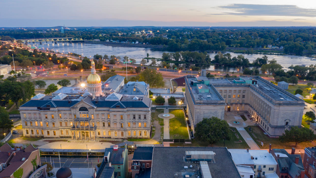 The capital statehouse of New Jersey lights up as the sun sets the Delaware River in the background city of Trenton.