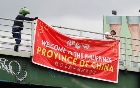 Traffic enforcers remove a banner reading "Welcome to the Philippines, Province of China" hanging on an overpass along the C5 road intersection in Taguig, Metro Manila, Philippines July 12, 2018. REUTERS/Erik De Castro