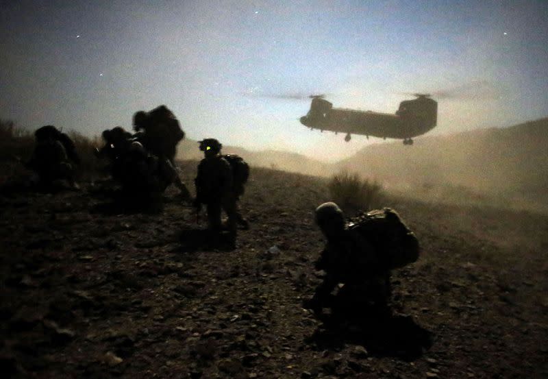 FILE PHOTO: U.S. and Afghan soldiers take a knee near a U.S. Army Chinook during an operation near the town of Walli Was in Paktika province