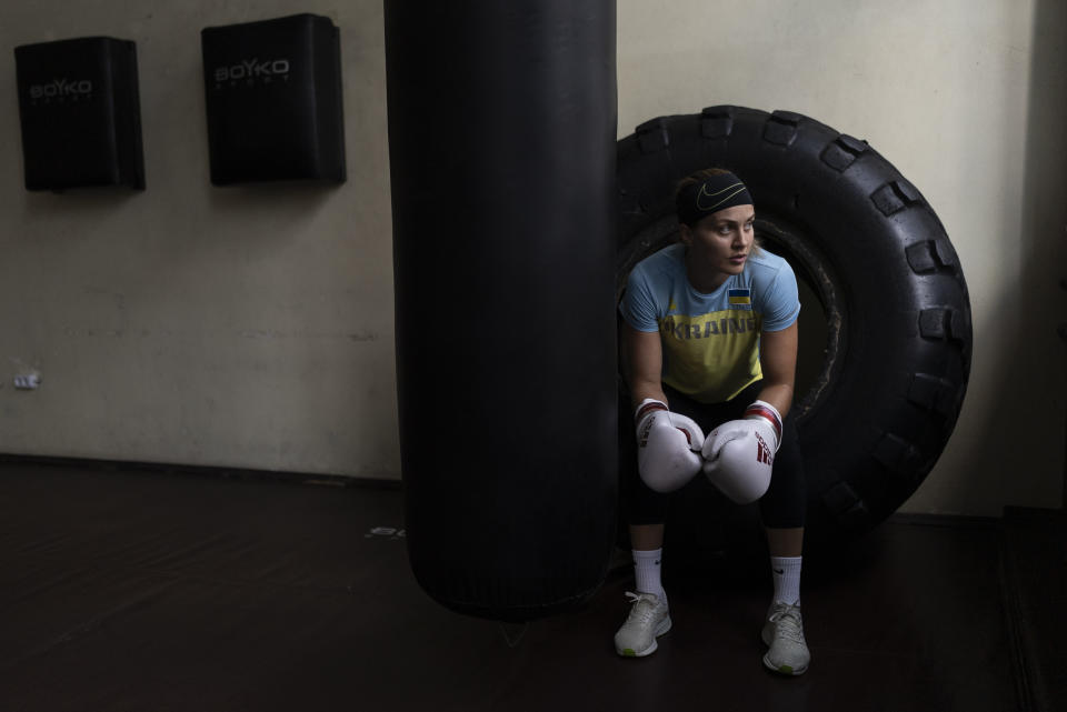 La boxeadora ucraniana Anna Lysenko sentada en un neumático durante un descanso de un entrenamiento en el Kiko Boxing Club de Kiev, Ucrania, el martes 11 de julio de 2023. (AP Foto/Jae C. Hong)