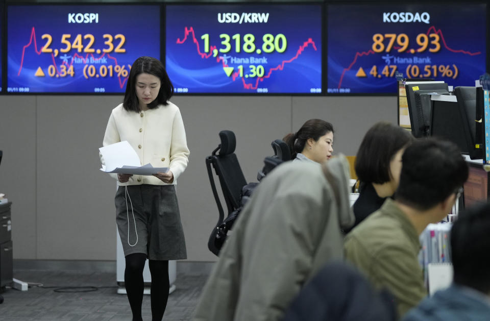A currency trader passes by the screens showing the Korea Composite Stock Price Index (KOSPI), left, and the foreign exchange rate between U.S. dollar and South Korean won, center, at the foreign exchange dealing room of the KEB Hana Bank headquarters in Seoul, South Korea, Thursday, Jan. 11, 2024. Asian shares advanced Thursday on the back of Wall Street’s climb to a near-record high, as Tokyo’s benchmark surged to a 34-year high.(AP Photo/Ahn Young-joon)